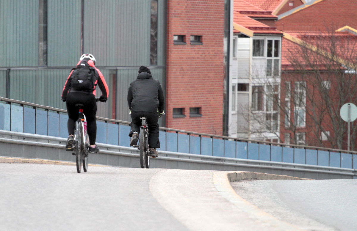 Pyöräilijöitä kevyen liikenteen väylällä kerrostalojen vieressä