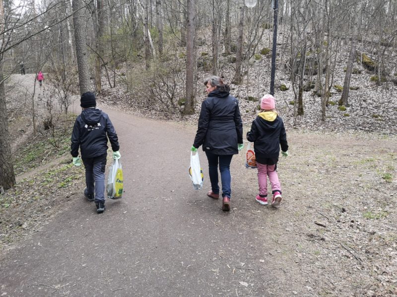 Kaksi lasta ja yksi aikuinen keräämässä roskia luontopolulla.